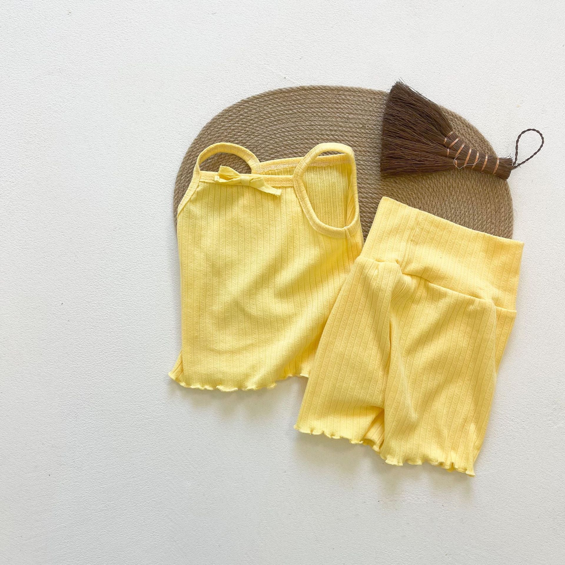 Baby girl wearing a ribbed knit sling top and shorts set with lettuce trim in yellow and apricot colors, perfect for summer.
