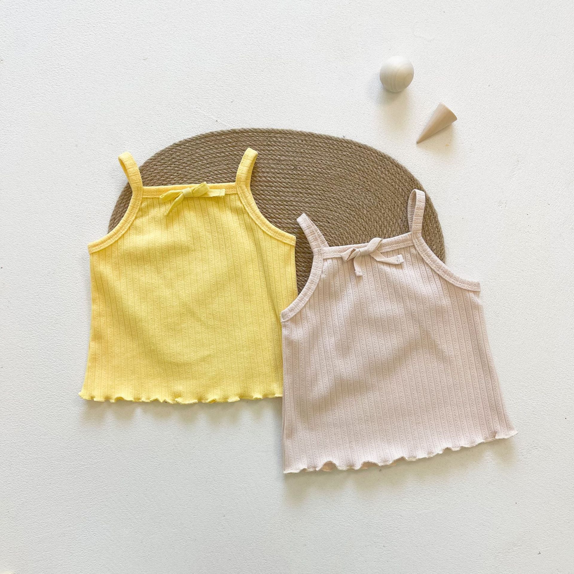 Baby girl wearing a ribbed knit sling top and shorts set with lettuce trim in yellow and apricot colors, perfect for summer.