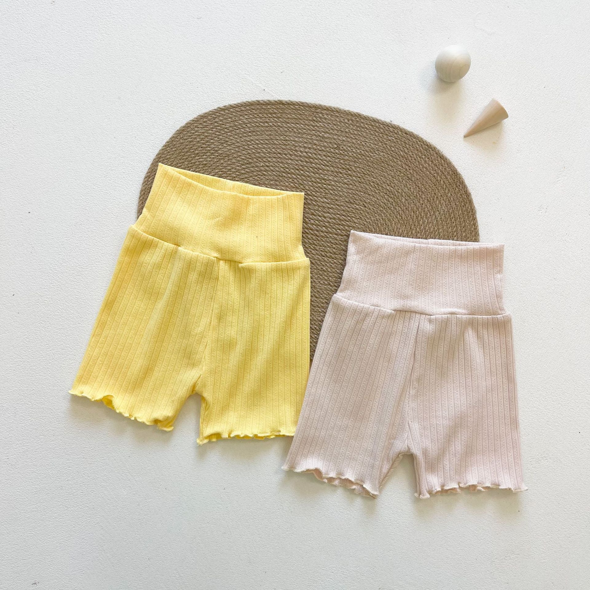 Baby girl wearing a ribbed knit sling top and shorts set with lettuce trim in yellow and apricot colors, perfect for summer.