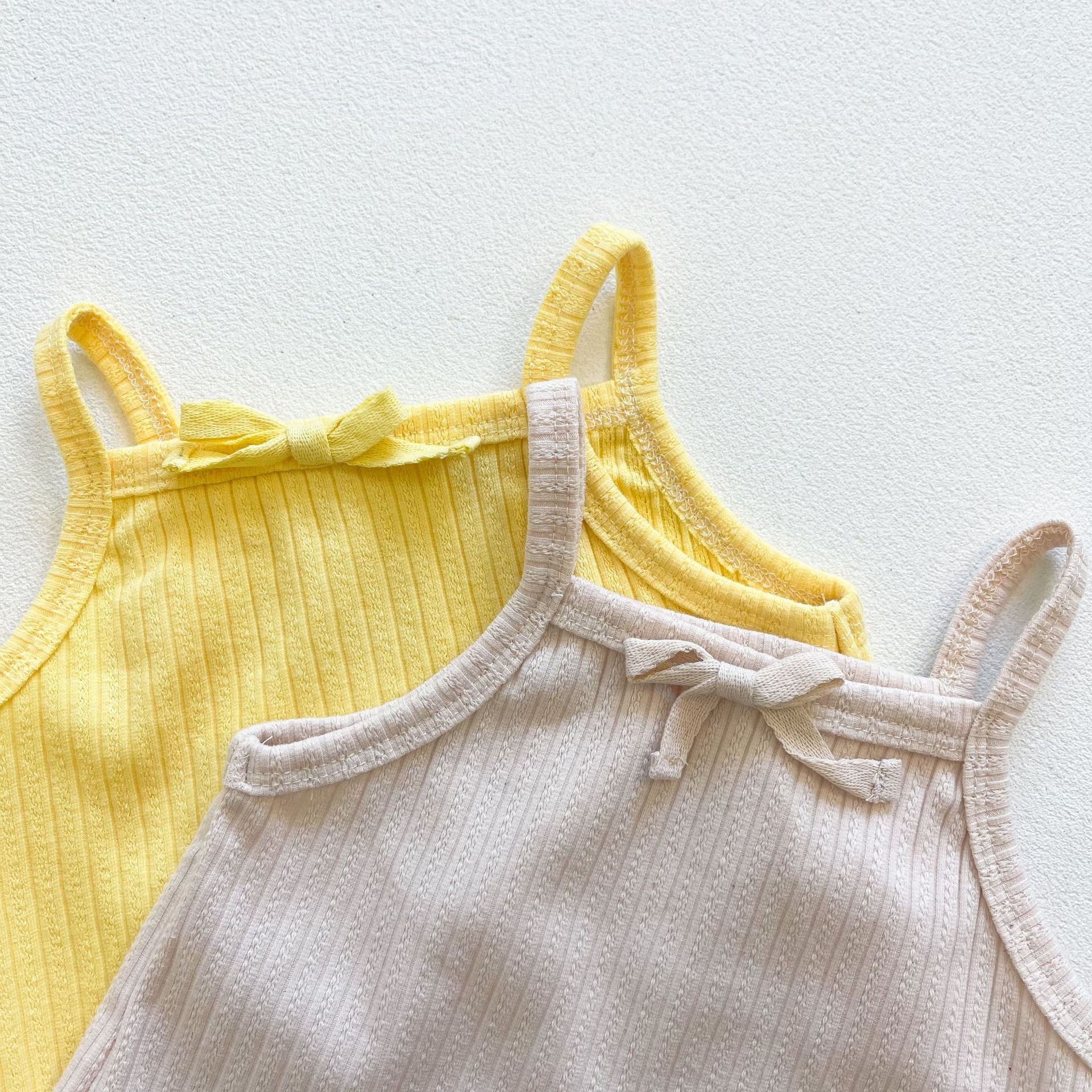 Baby girl wearing a ribbed knit sling top and shorts set with lettuce trim in yellow and apricot colors, perfect for summer.