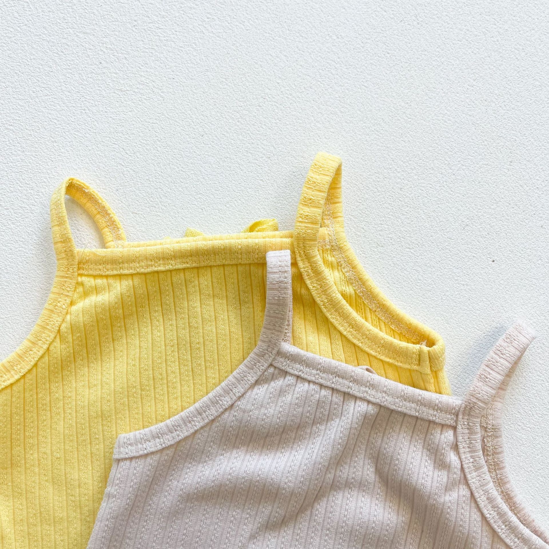 Baby girl wearing a ribbed knit sling top and shorts set with lettuce trim in yellow and apricot colors, perfect for summer.