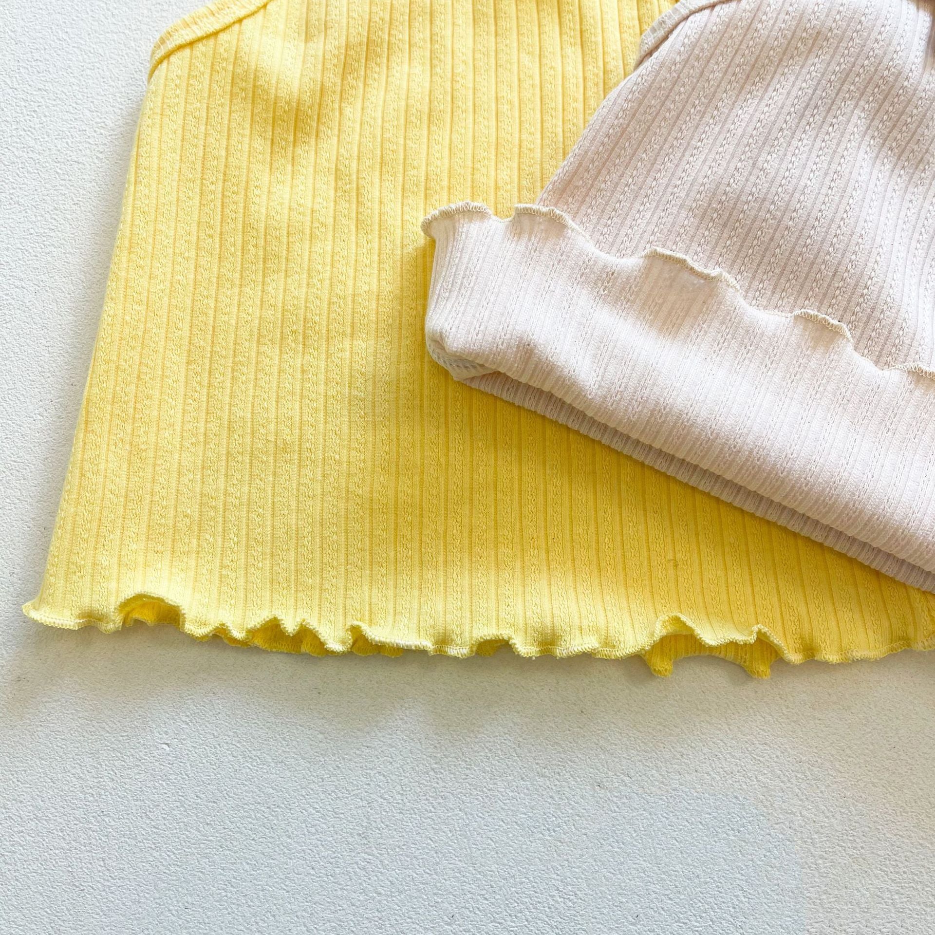 Baby girl wearing a ribbed knit sling top and shorts set with lettuce trim in yellow and apricot colors, perfect for summer.