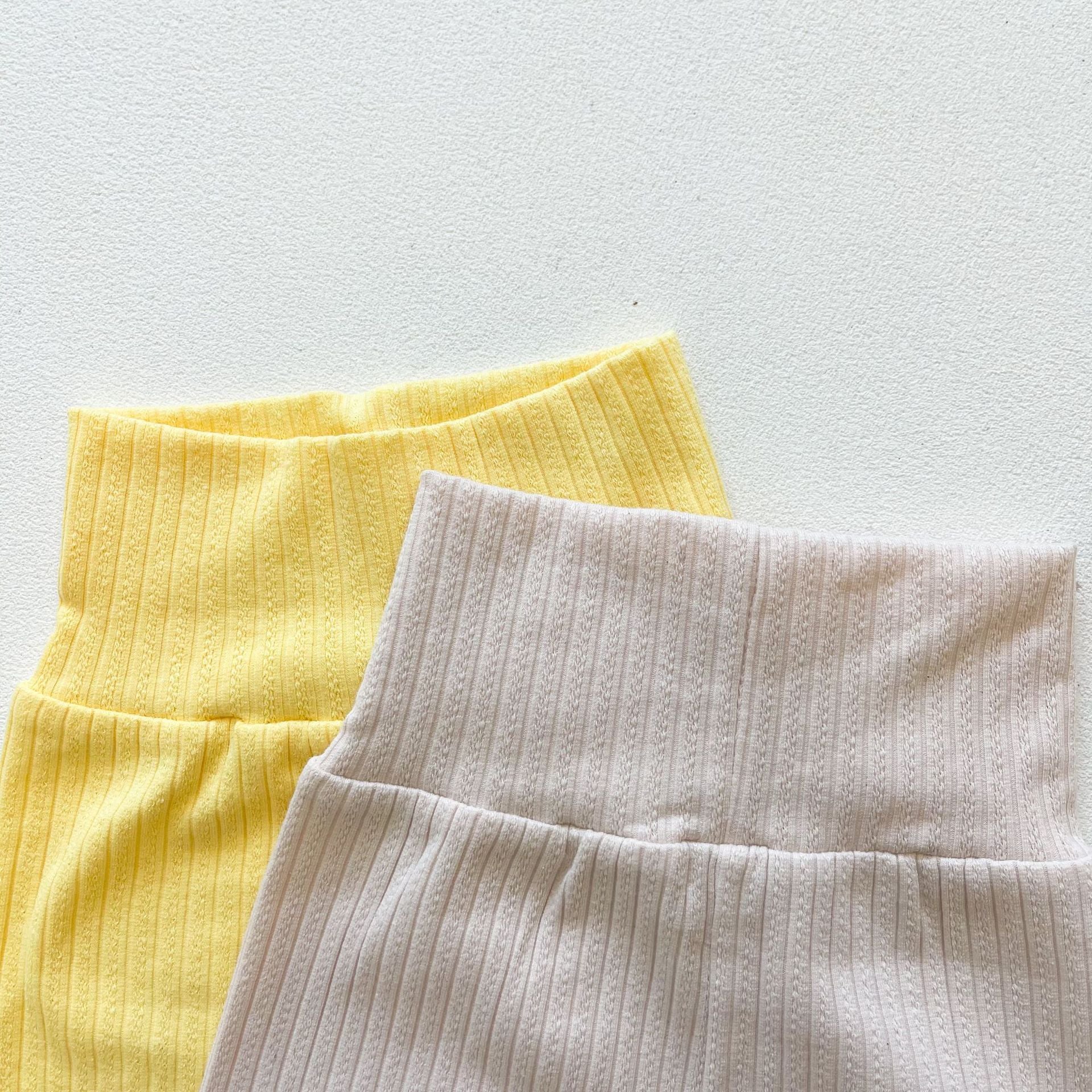 Baby girl wearing a ribbed knit sling top and shorts set with lettuce trim in yellow and apricot colors, perfect for summer.