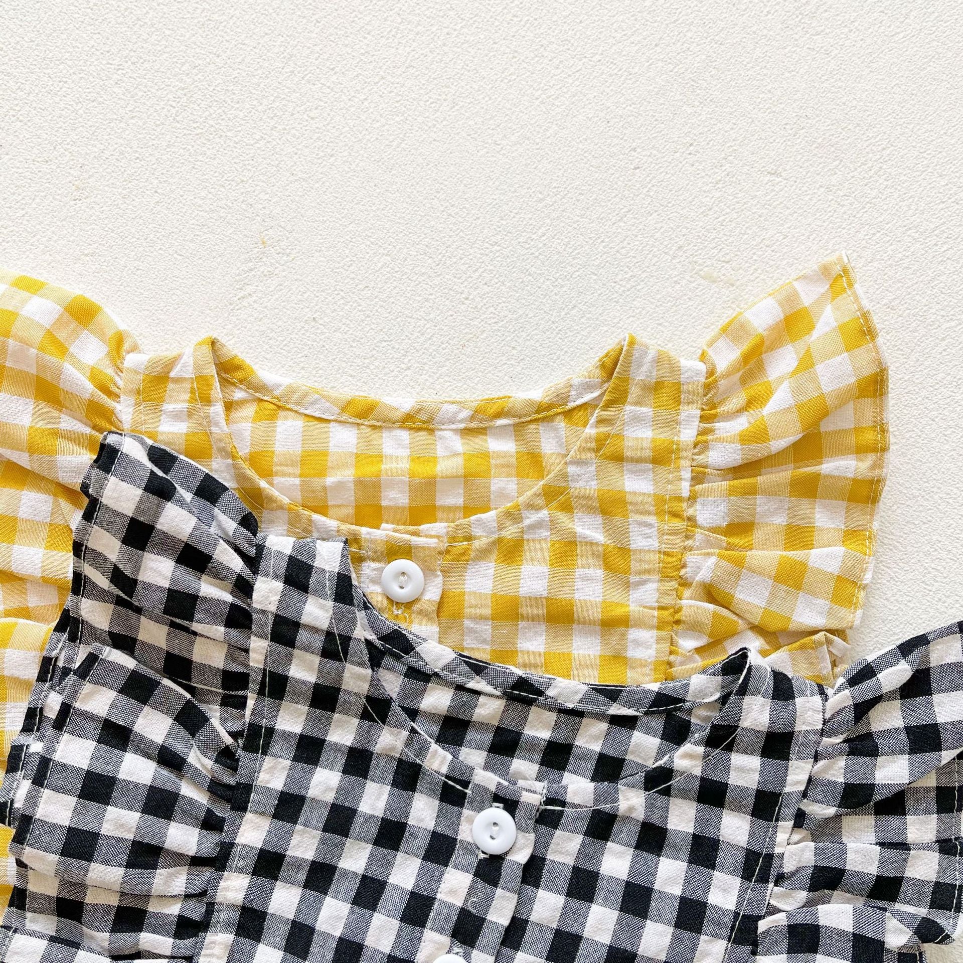 Baby girl sleeveless onesie featuring a stylish grid pattern in black and yellow, perfect for summer wear.