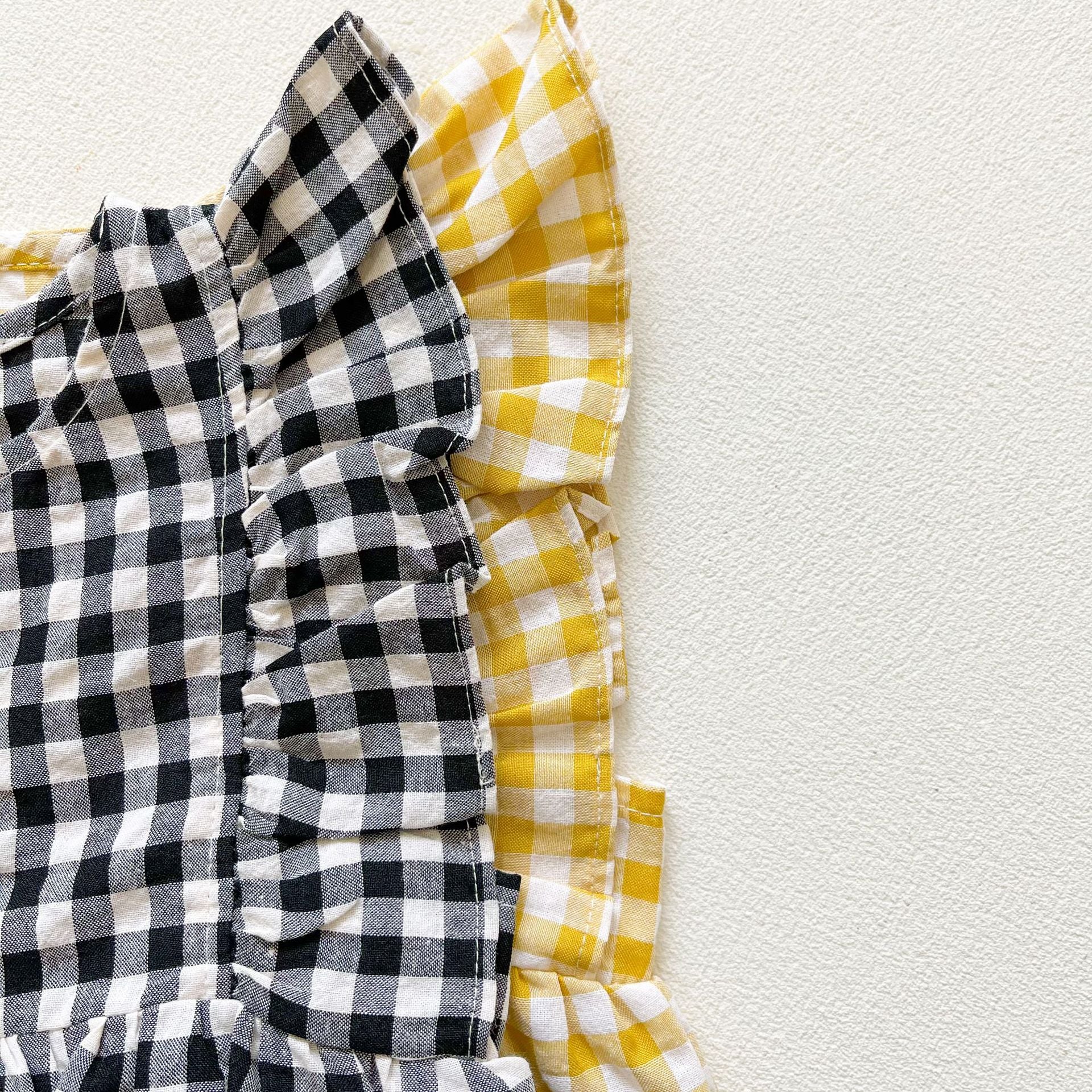 Baby girl sleeveless onesie featuring a stylish grid pattern in black and yellow, perfect for summer wear.