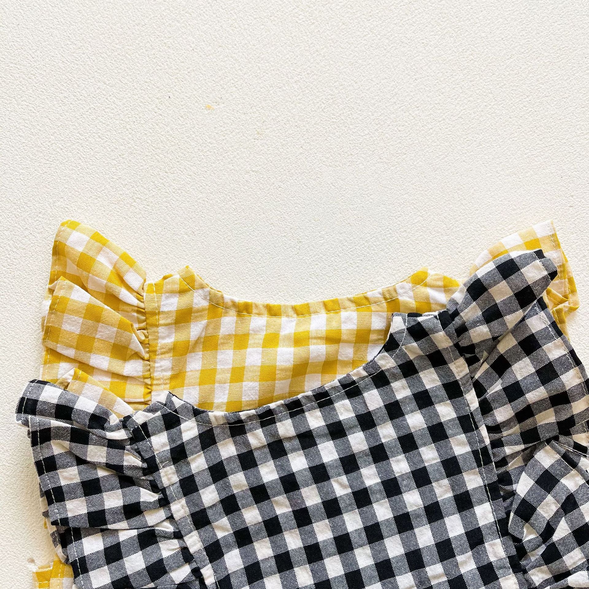 Baby girl sleeveless onesie featuring a stylish grid pattern in black and yellow, perfect for summer wear.