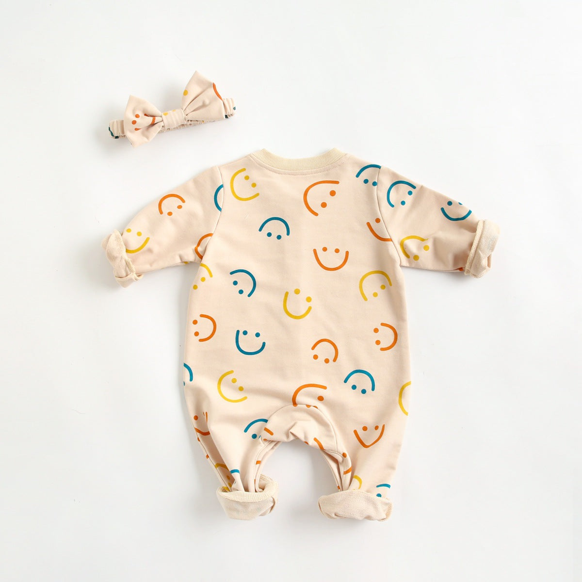 Baby girl long-sleeve romper with smiley print pattern in beige, featuring a single breasted design and covered button.