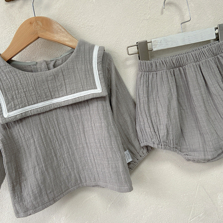 Baby girl wearing a solid color big lapel shirt and sailor shorts combo in grey and apricot, perfect for summer outings.