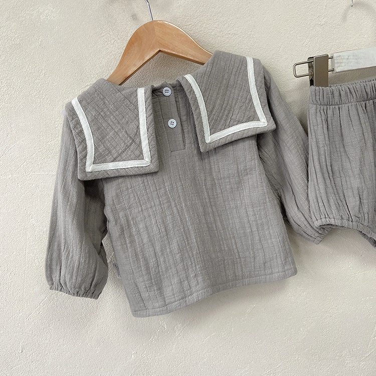 Baby girl wearing a solid color big lapel shirt and sailor shorts combo in grey and apricot, perfect for summer outings.