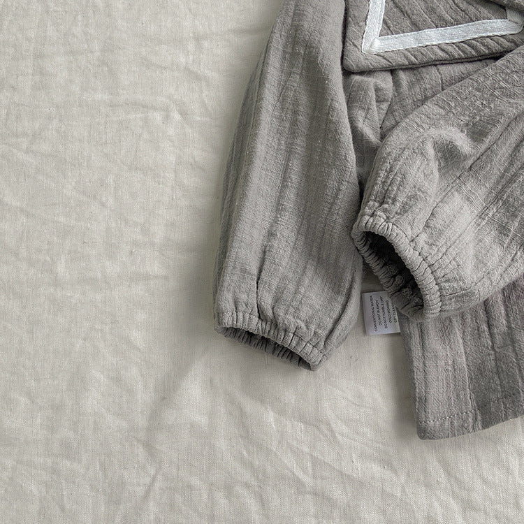 Baby girl wearing a solid color big lapel shirt and sailor shorts combo in grey and apricot, perfect for summer outings.