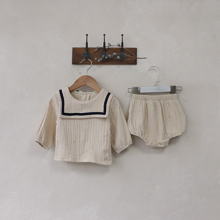 Baby girl wearing a solid color big lapel shirt and sailor shorts combo in grey and apricot, perfect for summer outings.