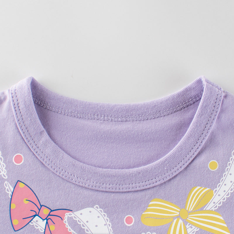 A stylish baby girl wearing a purple short sleeve tee with a solid color bow tie pattern, perfect for summer outings.