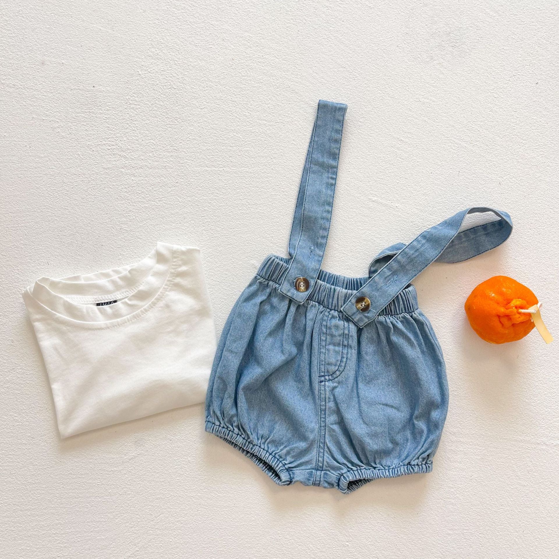 Baby girl wearing solid color denim fabric strap sling shorts rompers in blue, perfect for summer outings.