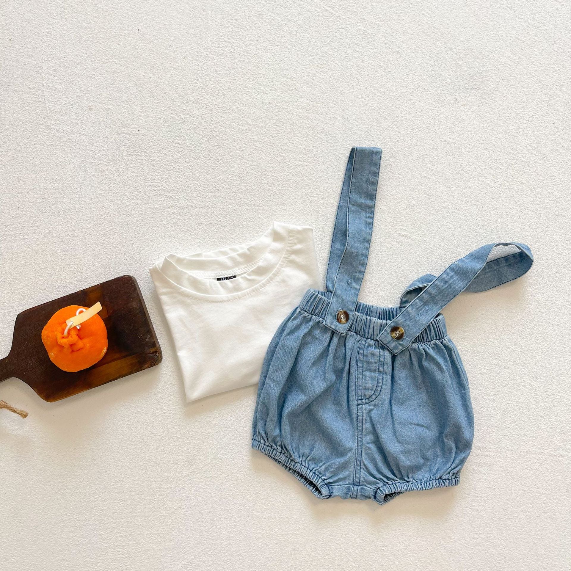 Baby girl wearing solid color denim fabric strap sling shorts rompers in blue, perfect for summer outings.