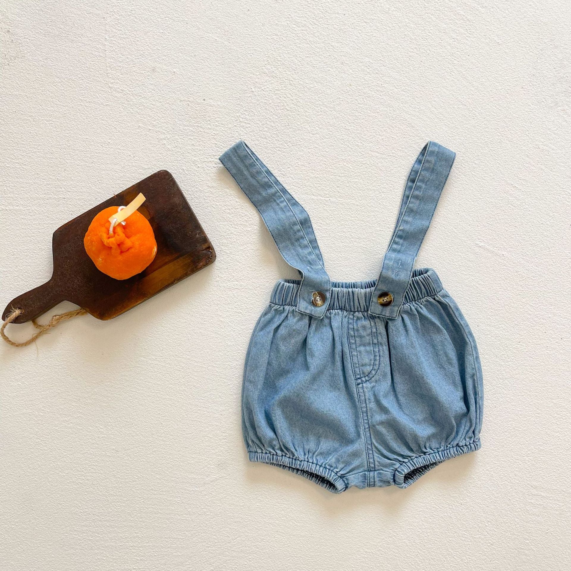 Baby girl wearing solid color denim fabric strap sling shorts rompers in blue, perfect for summer outings.