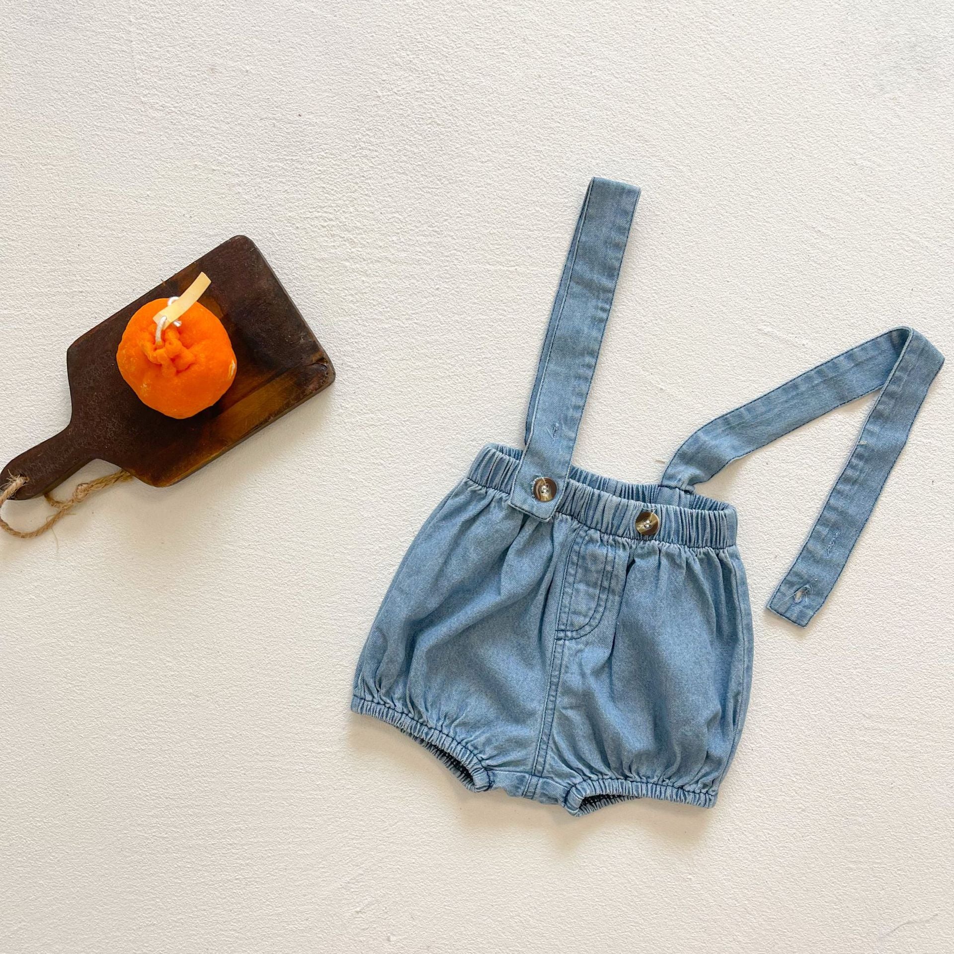 Baby girl wearing solid color denim fabric strap sling shorts rompers in blue, perfect for summer outings.