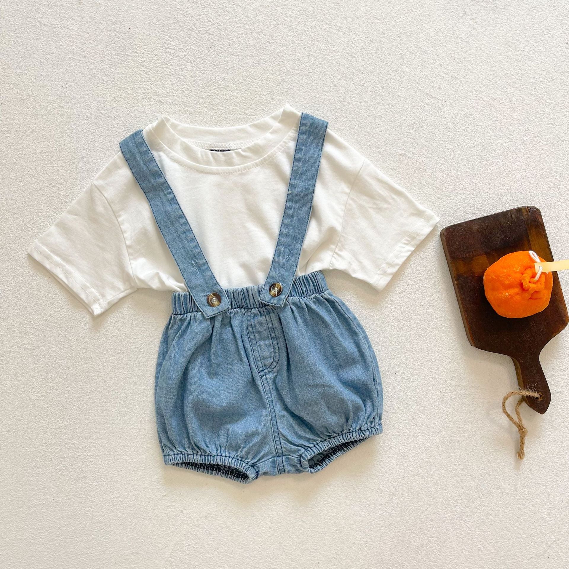 Baby girl wearing solid color denim fabric strap sling shorts rompers in blue, perfect for summer outings.