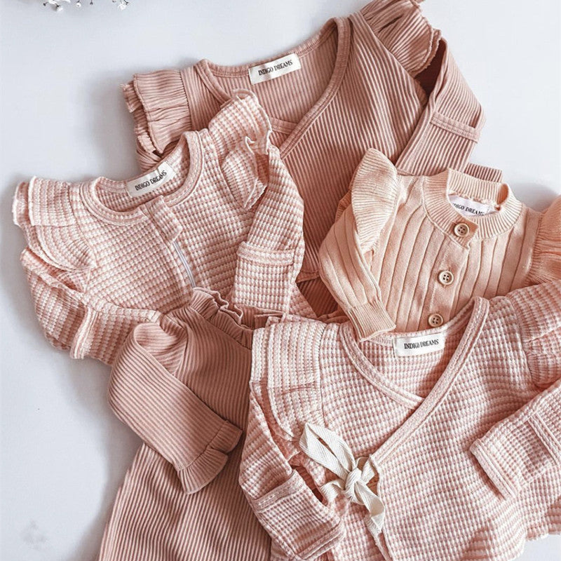 A two-piece baby girl outfit featuring a solid color long sleeve top and matching pants made from pure cotton, available in white, pink, khaki, and brown.