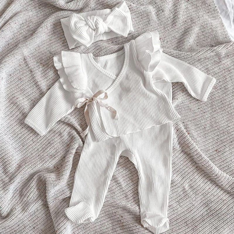 A two-piece baby girl outfit featuring a solid color long sleeve top and matching pants made from pure cotton, available in white, pink, khaki, and brown.