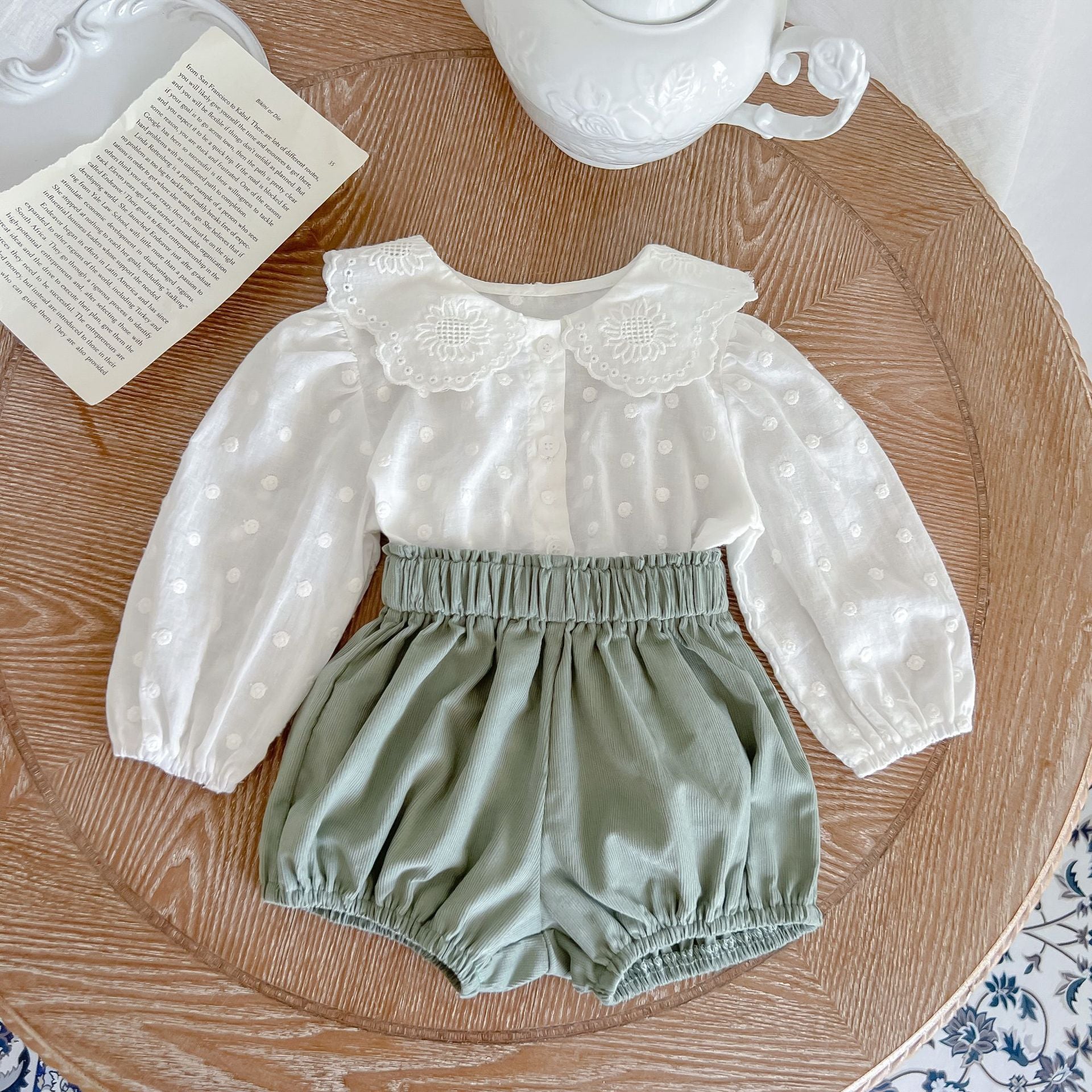 Baby girl wearing a solid color doll neck shirt and shorts set in white and green, showcasing a stylish and comfortable outfit.