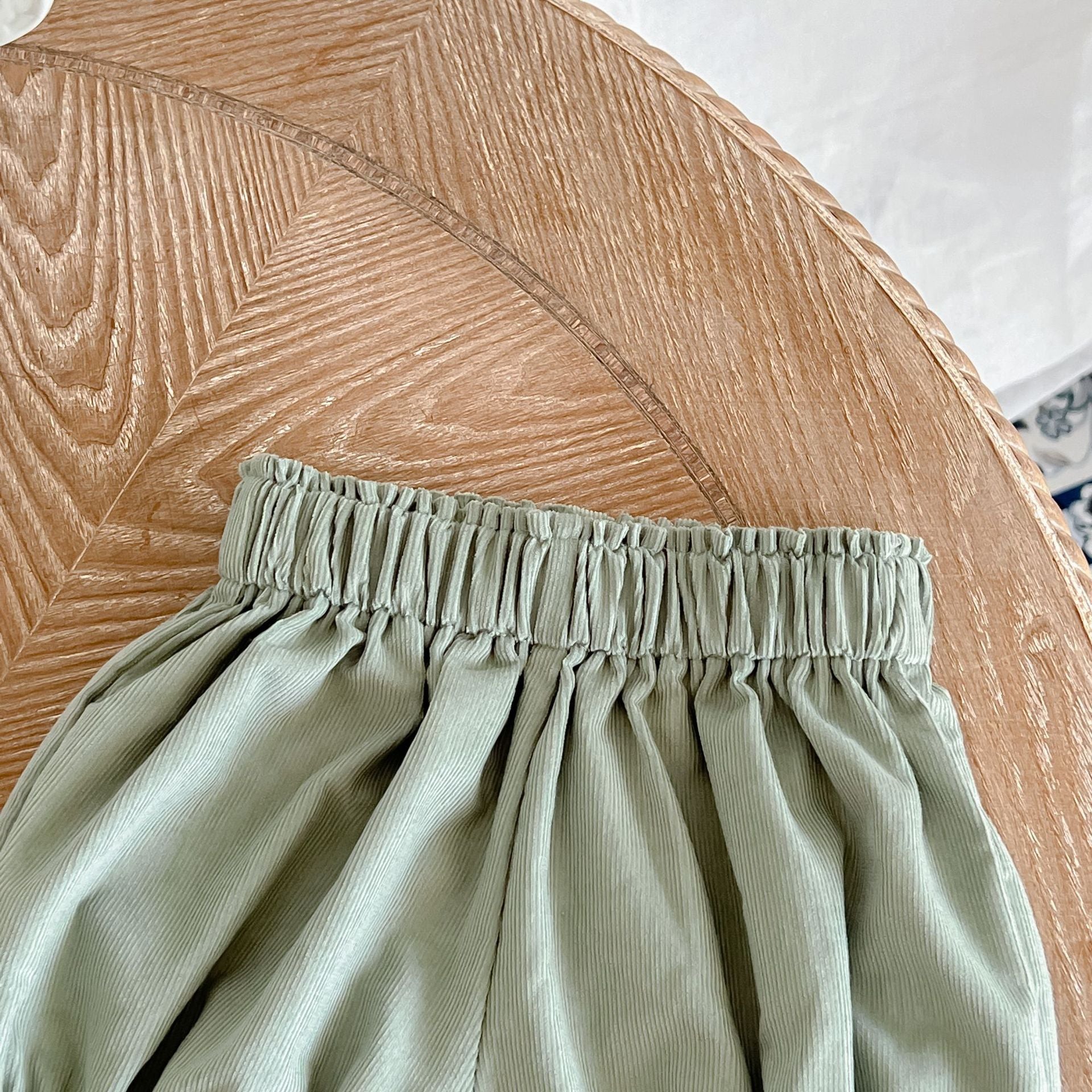 Baby girl wearing a solid color doll neck shirt and shorts set in white and green, showcasing a stylish and comfortable outfit.