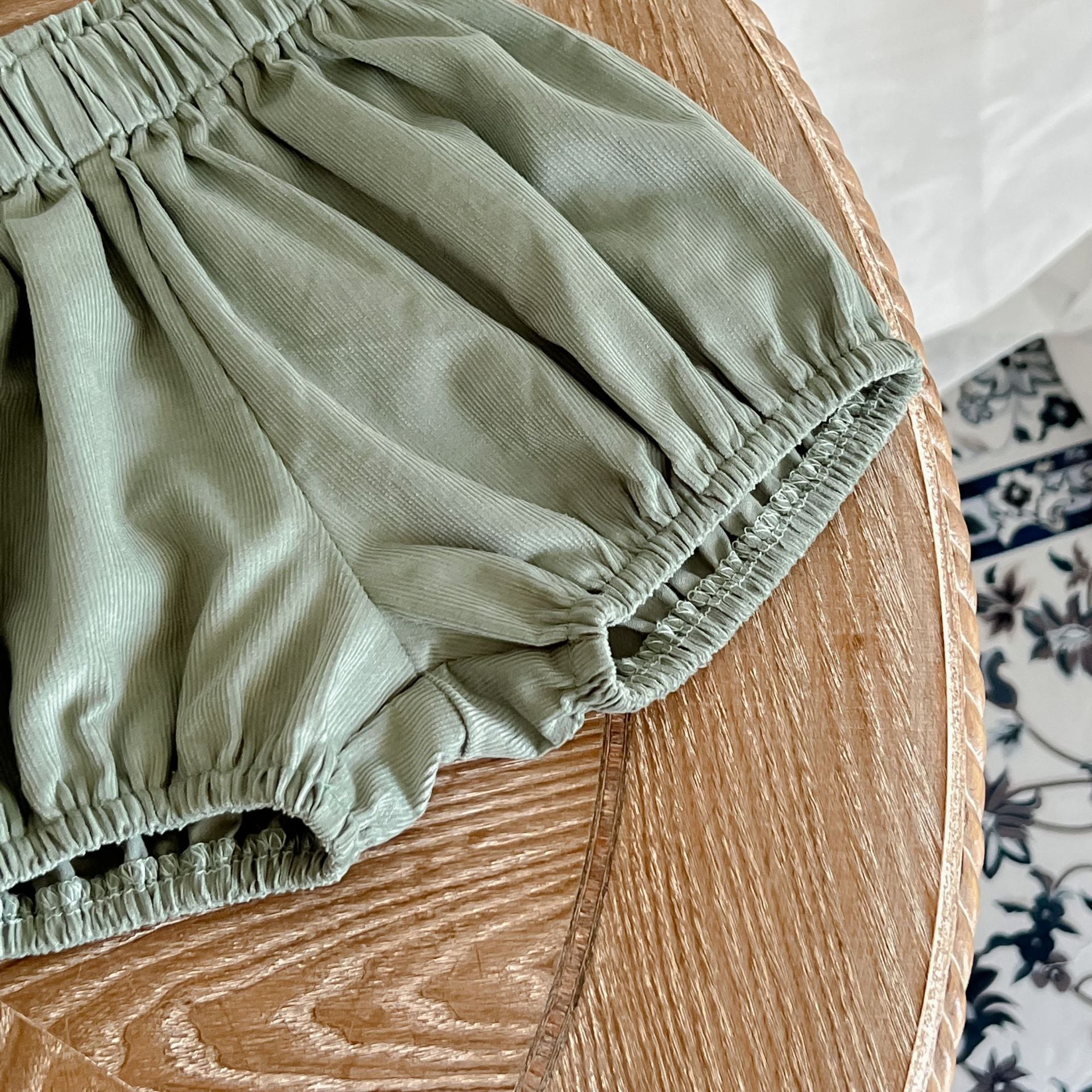 Baby girl wearing a solid color doll neck shirt and shorts set in white and green, showcasing a stylish and comfortable outfit.