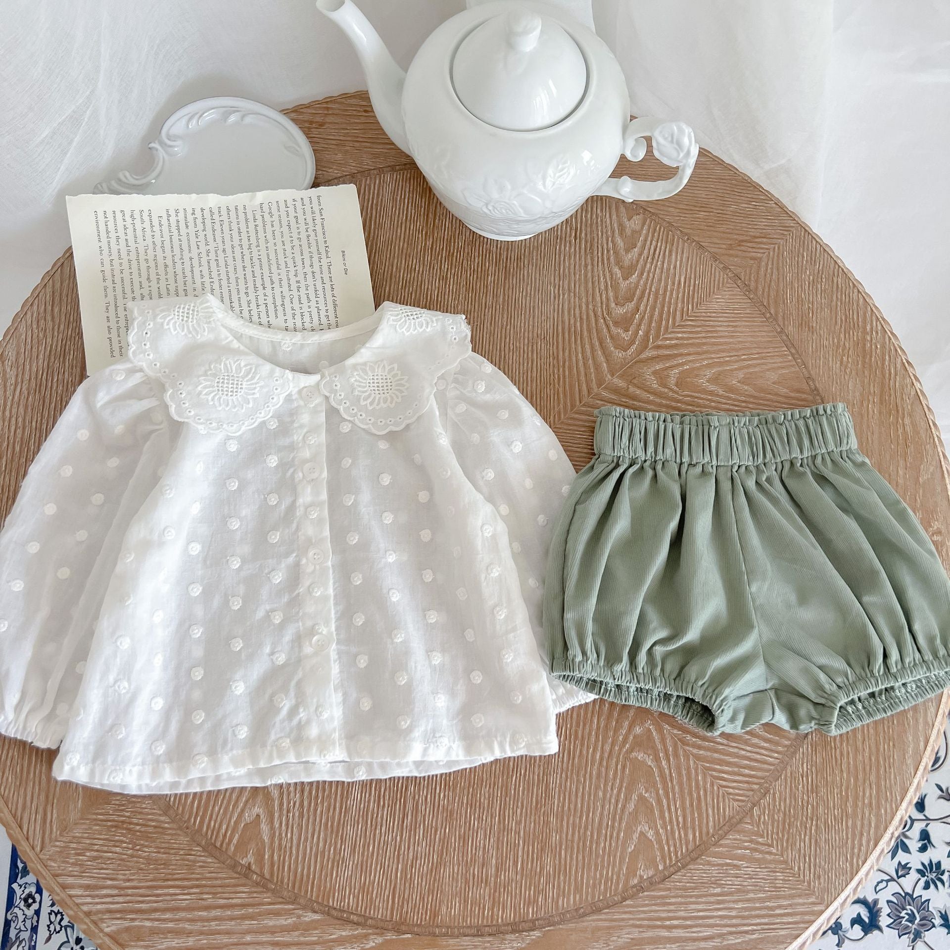 Baby girl wearing a solid color doll neck shirt and shorts set in white and green, showcasing a stylish and comfortable outfit.