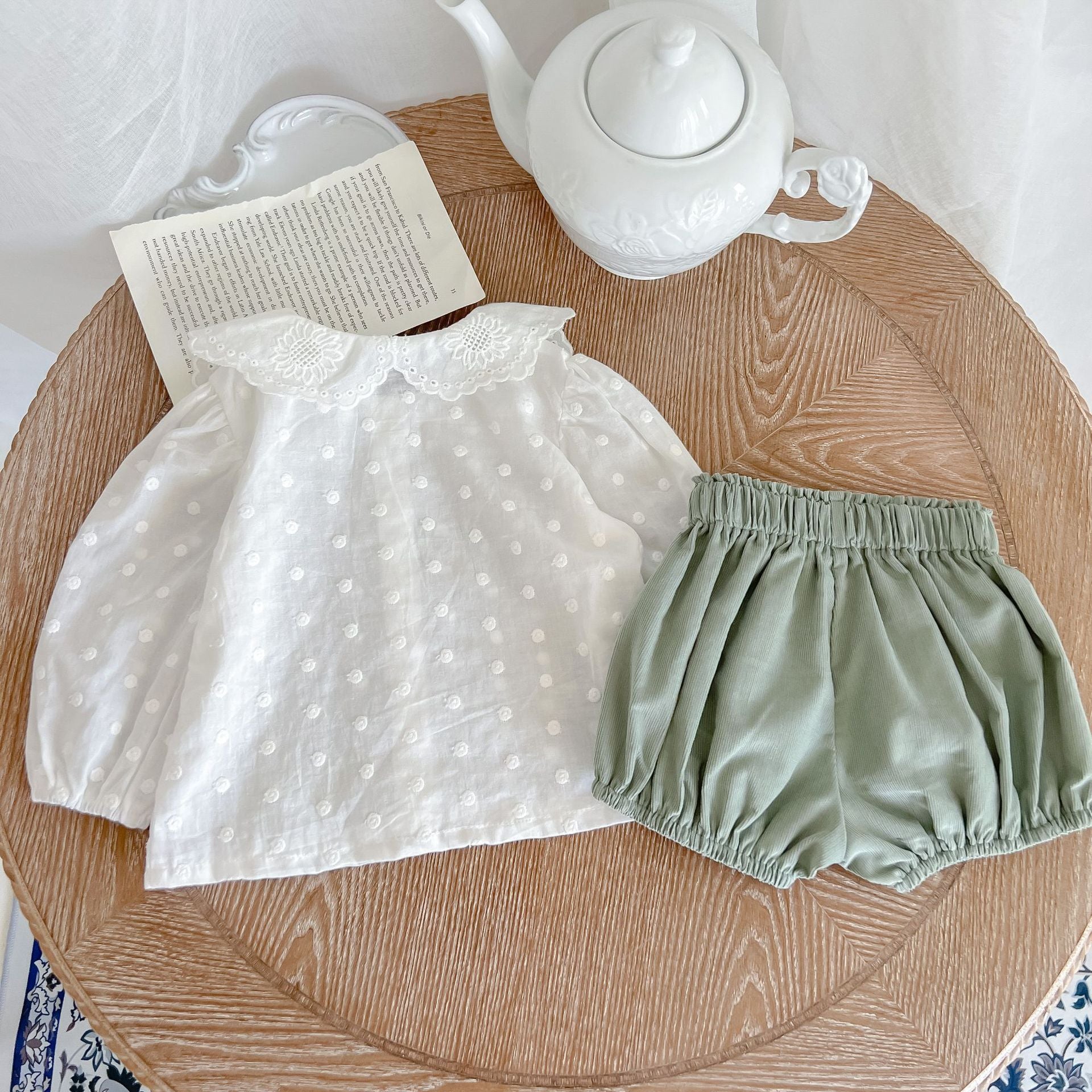 Baby girl wearing a solid color doll neck shirt and shorts set in white and green, showcasing a stylish and comfortable outfit.