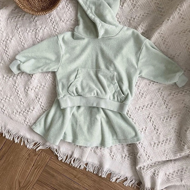 Baby girl wearing a soft cotton hoodie and skirt set in green, showcasing comfort and style.