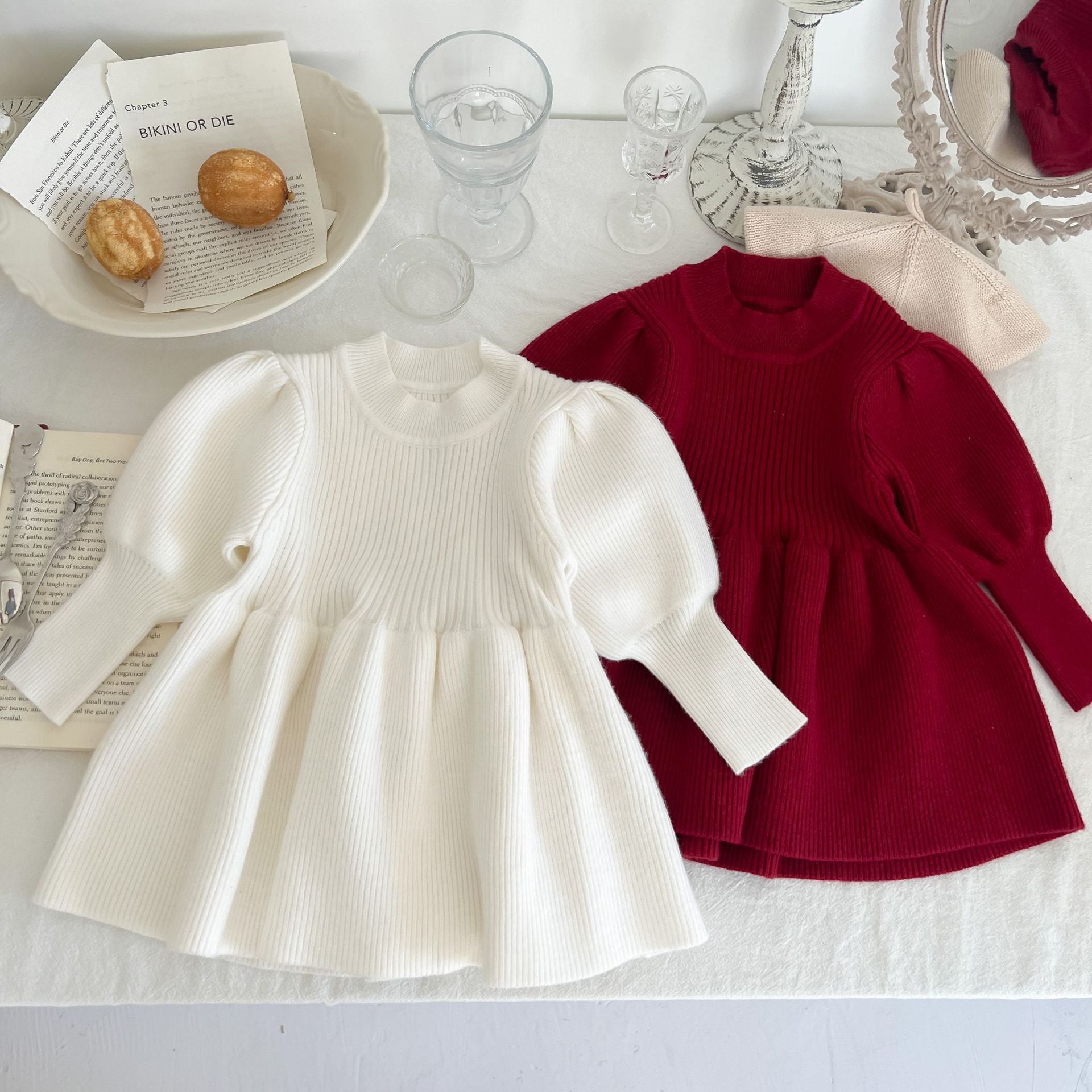 A cozy baby girl knitting dress with lantern sleeves in solid white and red colors, perfect for autumn wear.