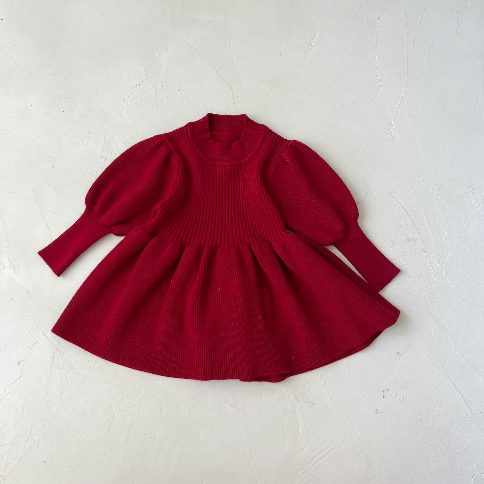 A cozy baby girl knitting dress with lantern sleeves in solid white and red colors, perfect for autumn wear.