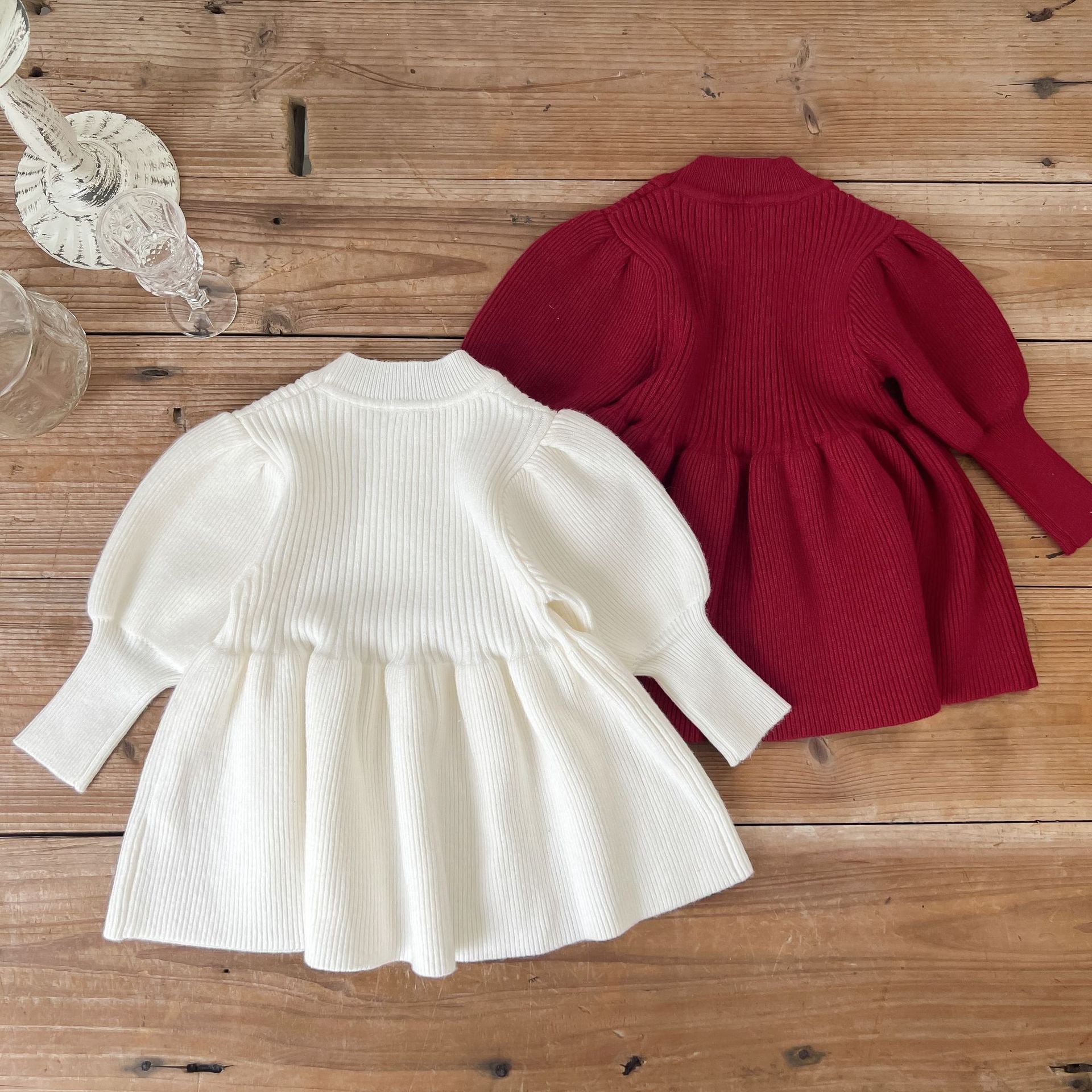 A cozy baby girl knitting dress with lantern sleeves in solid white and red colors, perfect for autumn wear.