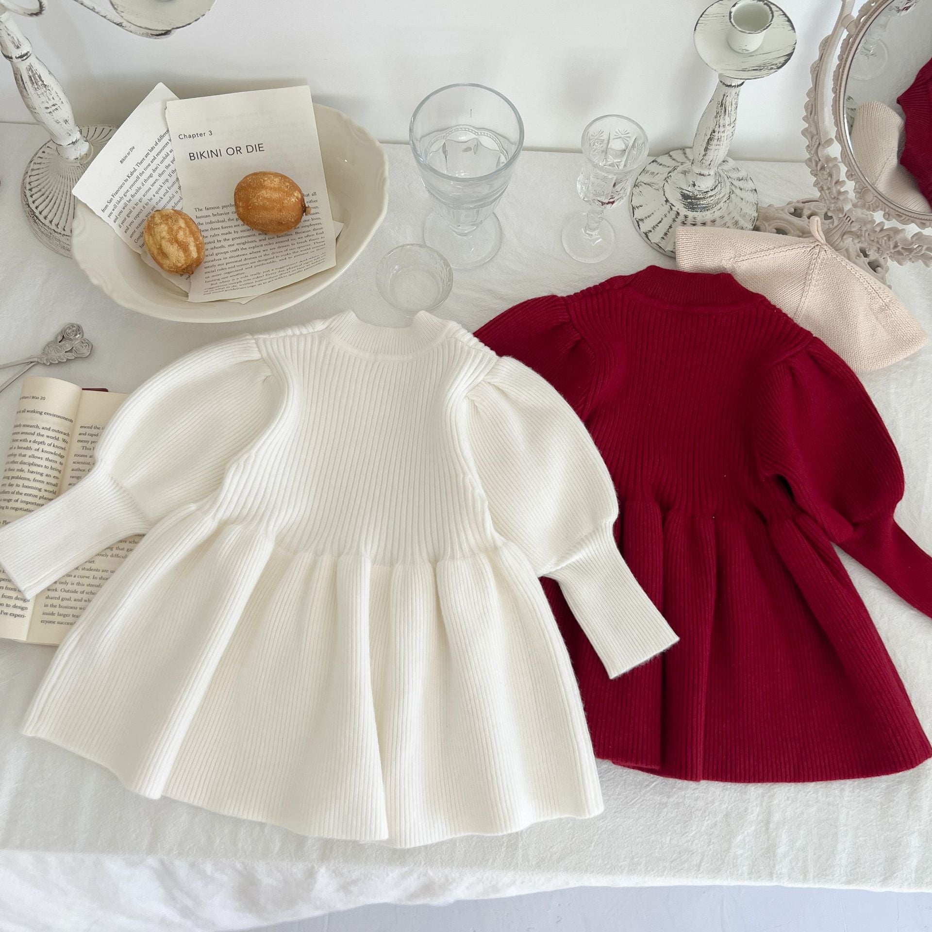 A cozy baby girl knitting dress with lantern sleeves in solid white and red colors, perfect for autumn wear.