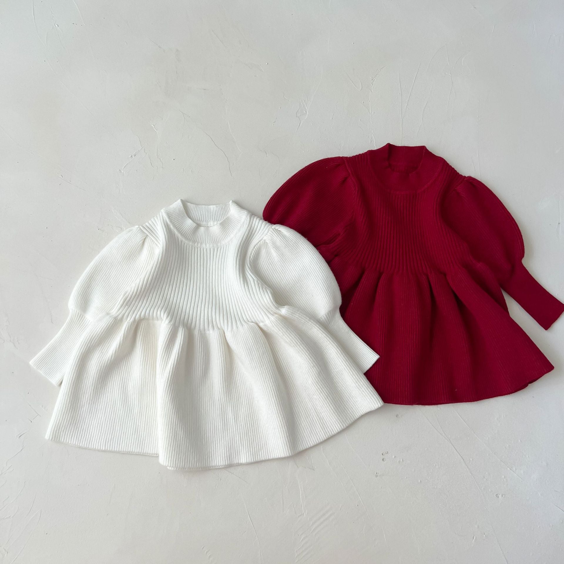 A cozy baby girl knitting dress with lantern sleeves in solid white and red colors, perfect for autumn wear.
