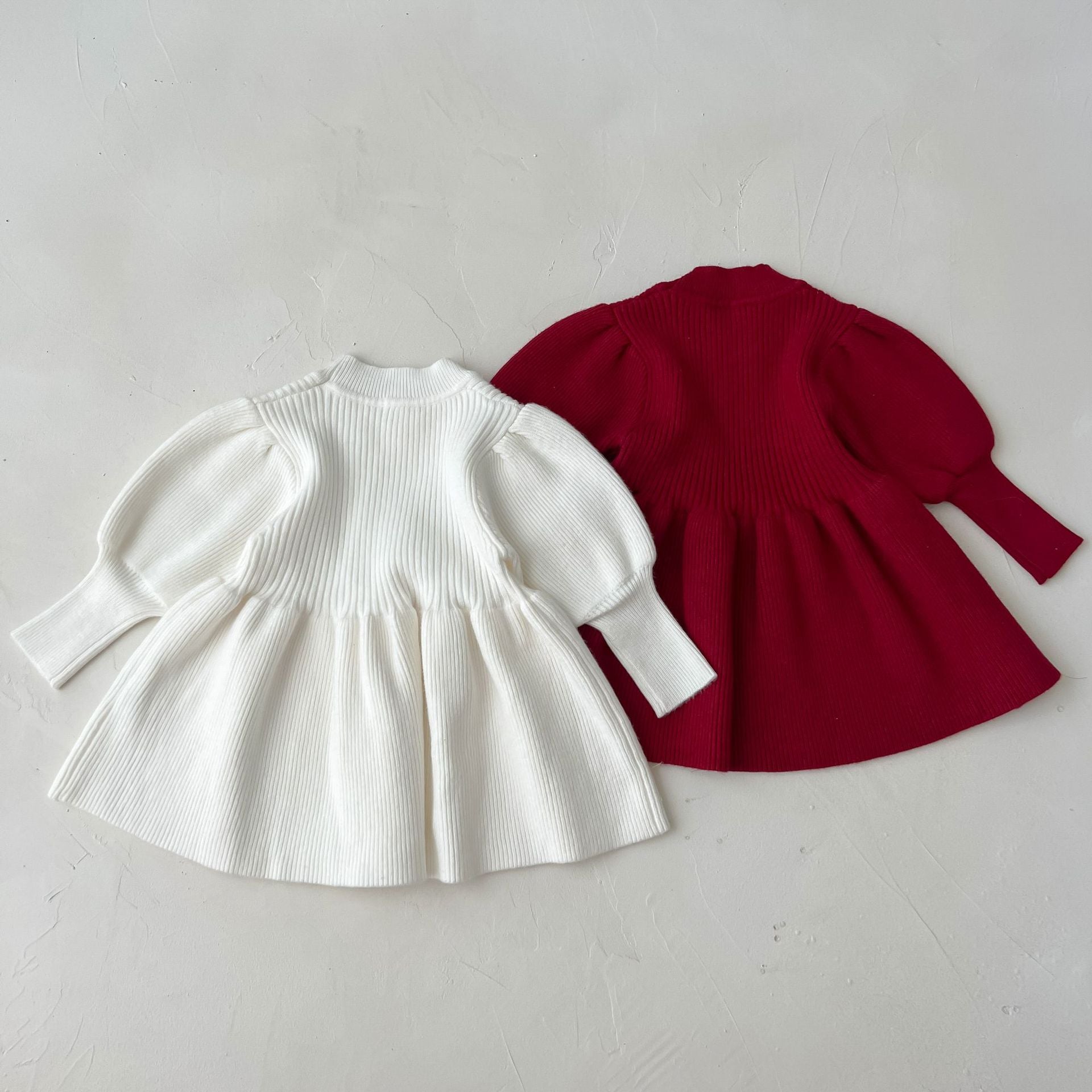 A cozy baby girl knitting dress with lantern sleeves in solid white and red colors, perfect for autumn wear.