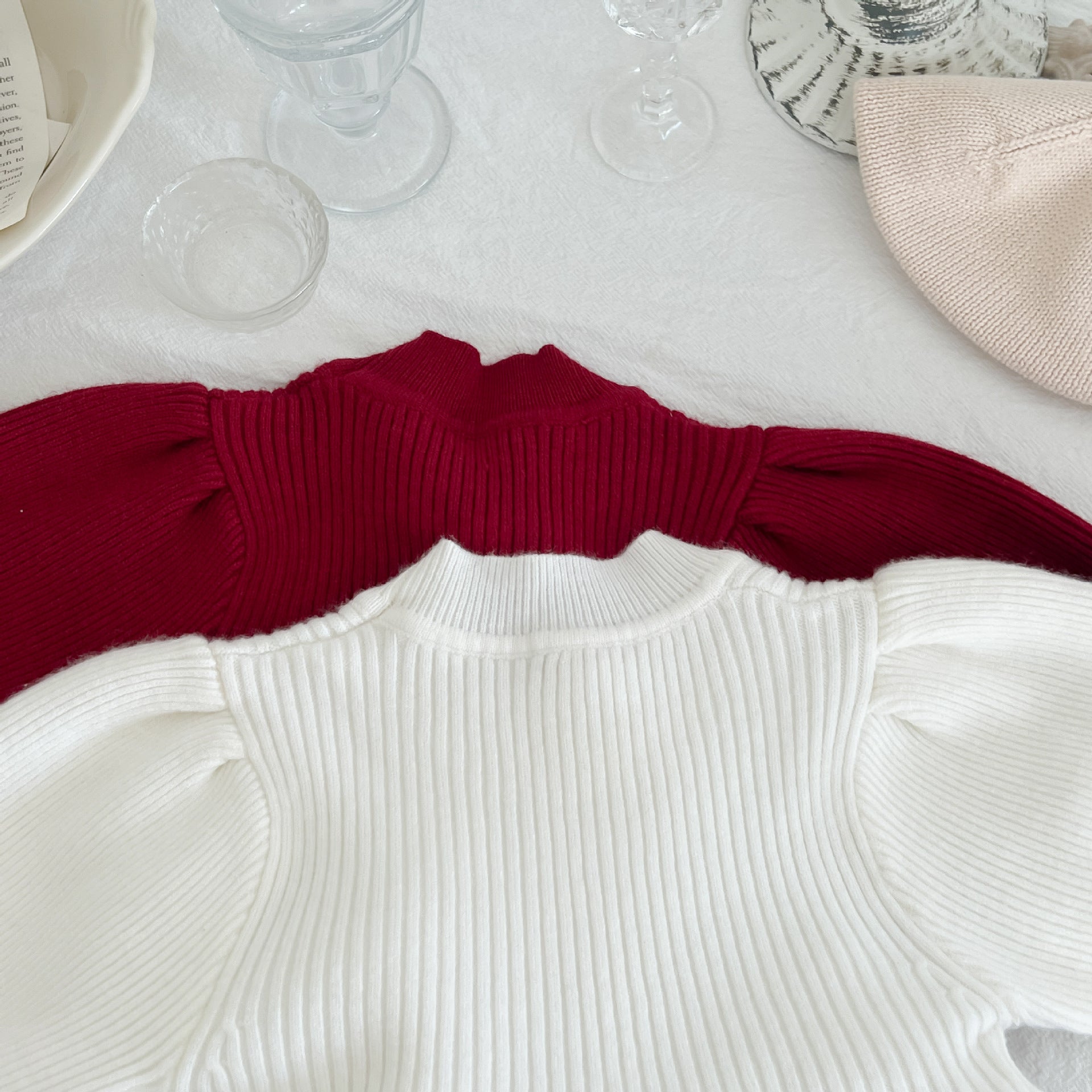A cozy baby girl knitting dress with lantern sleeves in solid white and red colors, perfect for autumn wear.