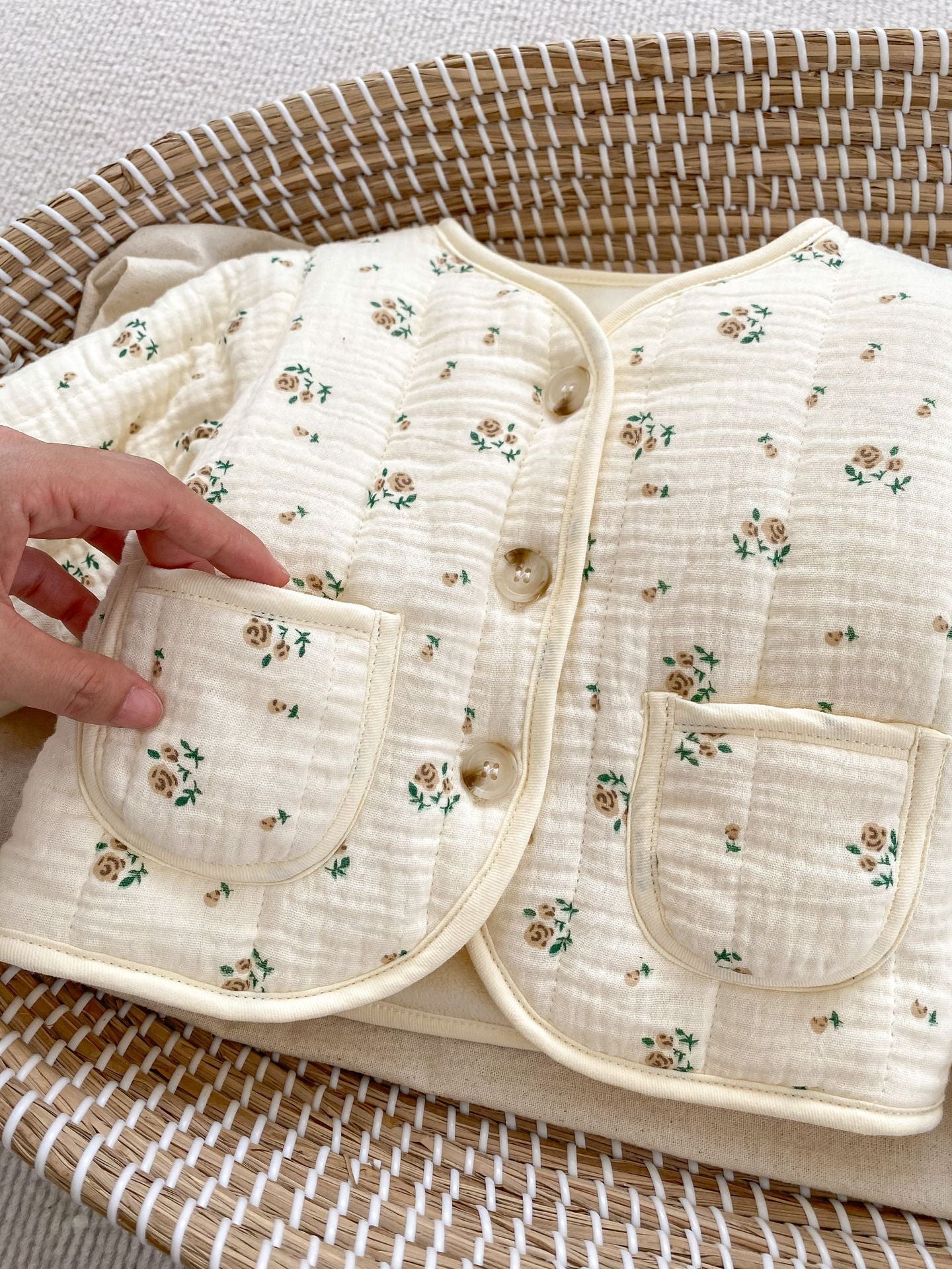 Hand touching floral baby jacket.