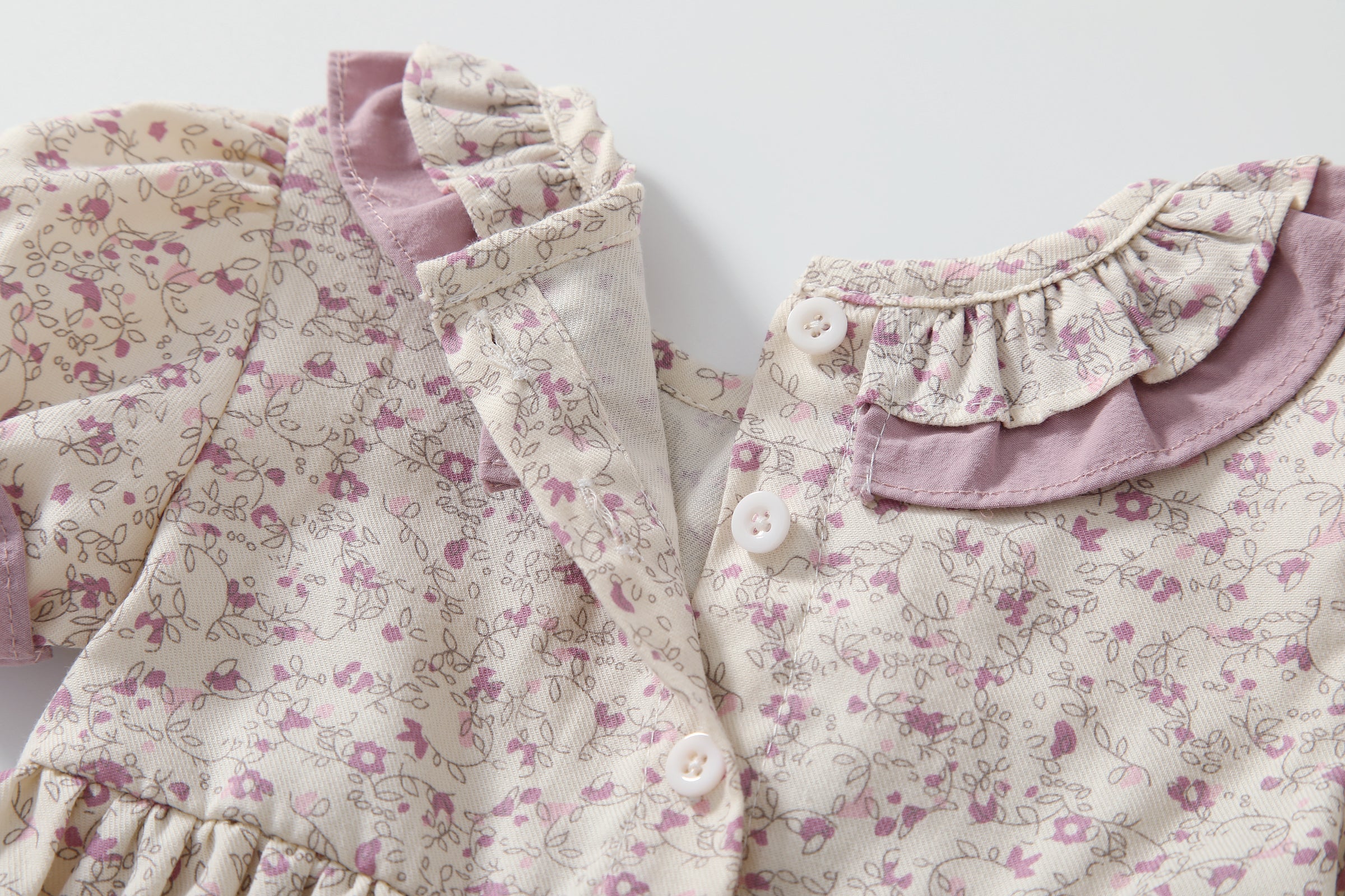 Baby girl wearing a floral print doll collar onesie with a matching headband, showcasing a stylish summer outfit.