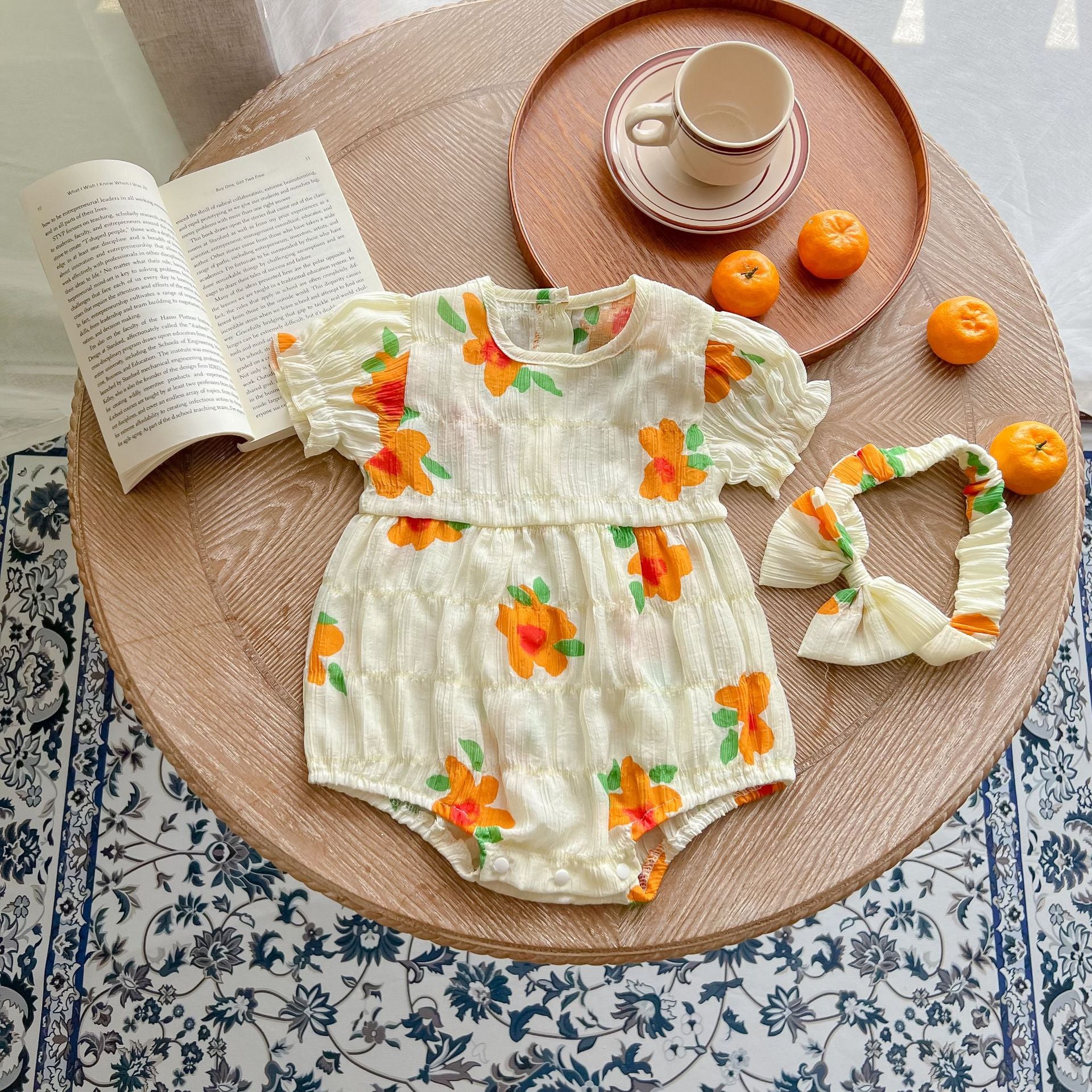 Baby girls floral print puff sleeved onesie in white, perfect for summer wear, featuring a vibrant flower pattern.