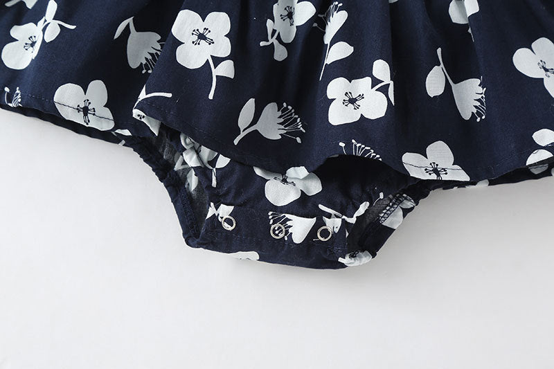 A cute baby girl wearing a floral print sleeveless dress, showcasing a vibrant design with an O-neck and single-breasted style, perfect for summer.