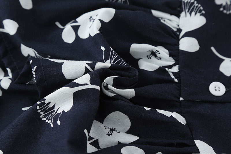 A cute baby girl wearing a floral print sleeveless dress, showcasing a vibrant design with an O-neck and single-breasted style, perfect for summer.