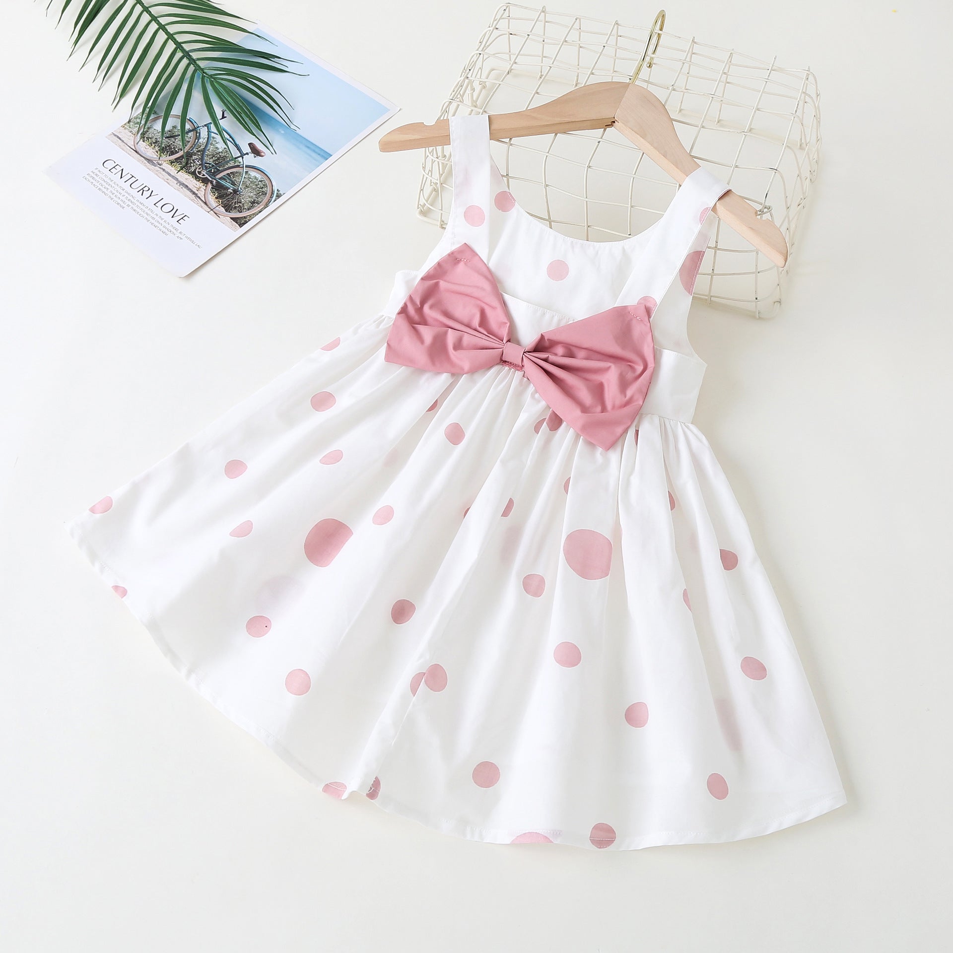 Baby girls' sleeveless dress featuring a polka dot pattern and a bow, available in pink, green, and yellow.
