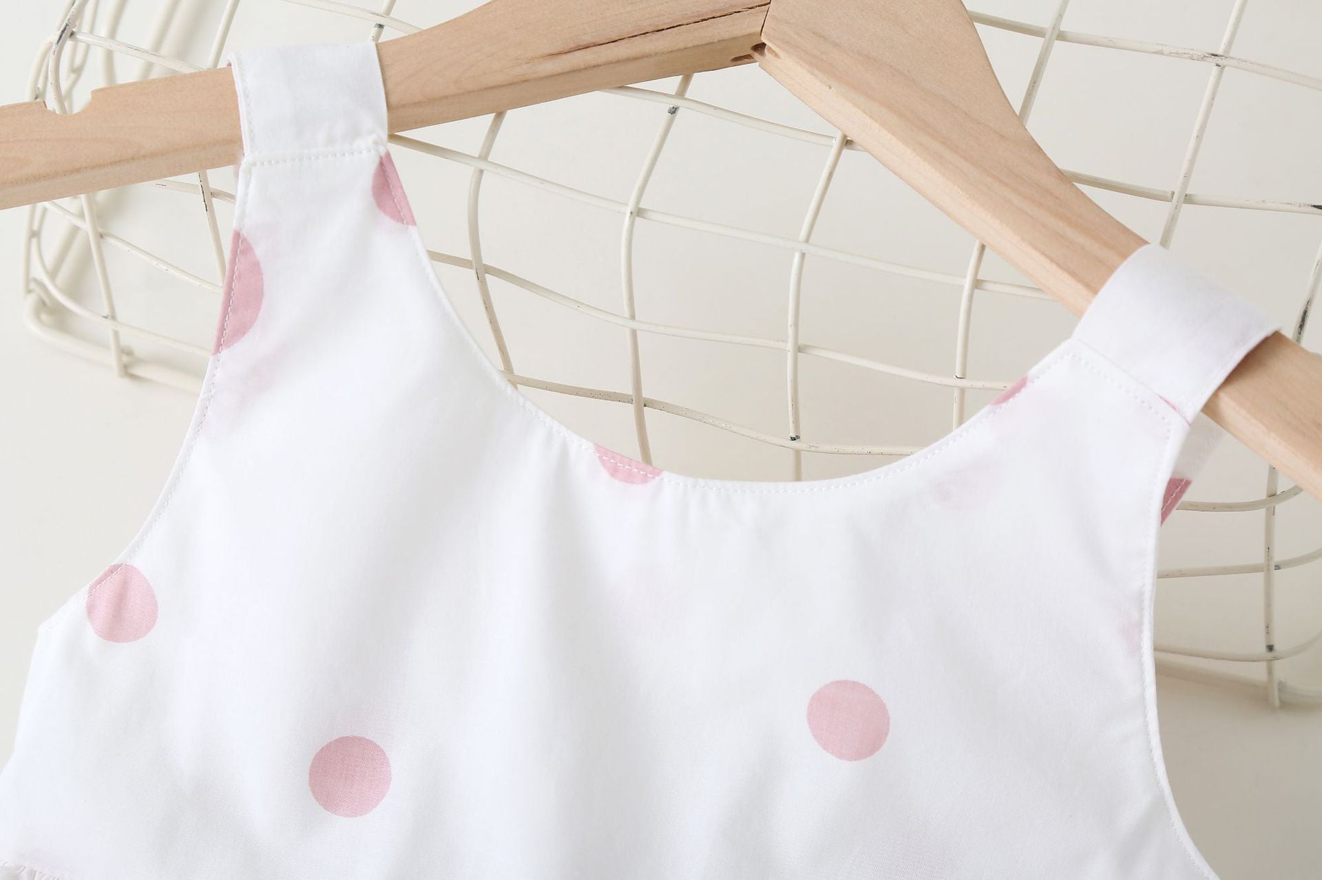 Baby girls' sleeveless dress featuring a polka dot pattern and a bow, available in pink, green, and yellow.