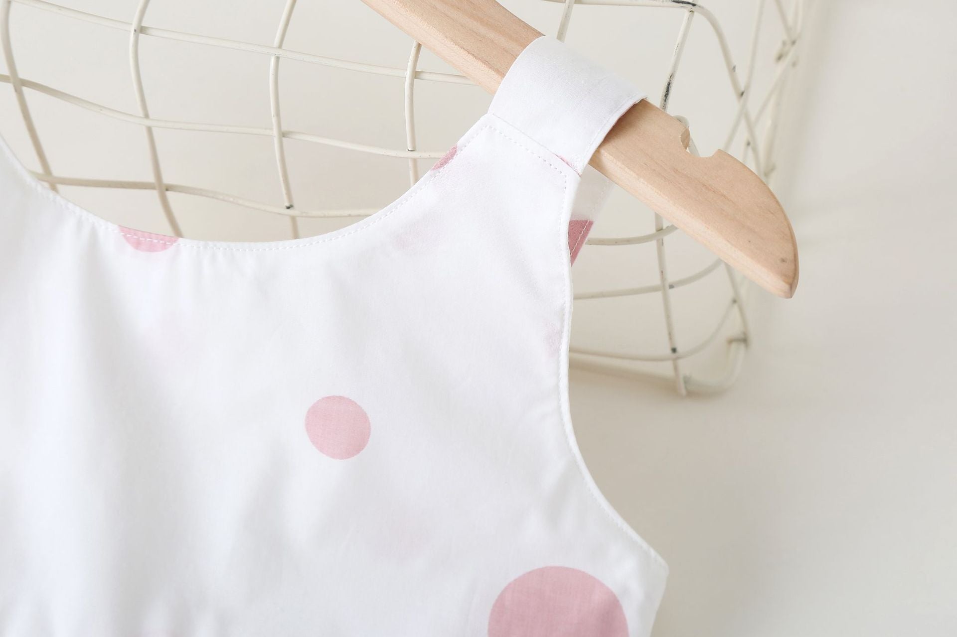 Baby girls' sleeveless dress featuring a polka dot pattern and a bow, available in pink, green, and yellow.