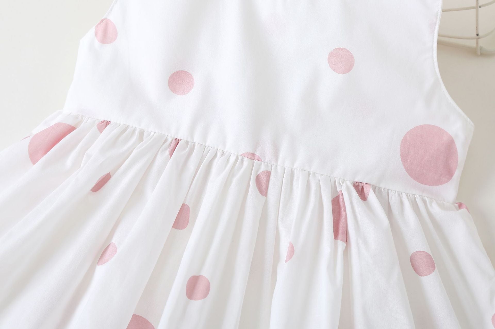 Baby girls' sleeveless dress featuring a polka dot pattern and a bow, available in pink, green, and yellow.