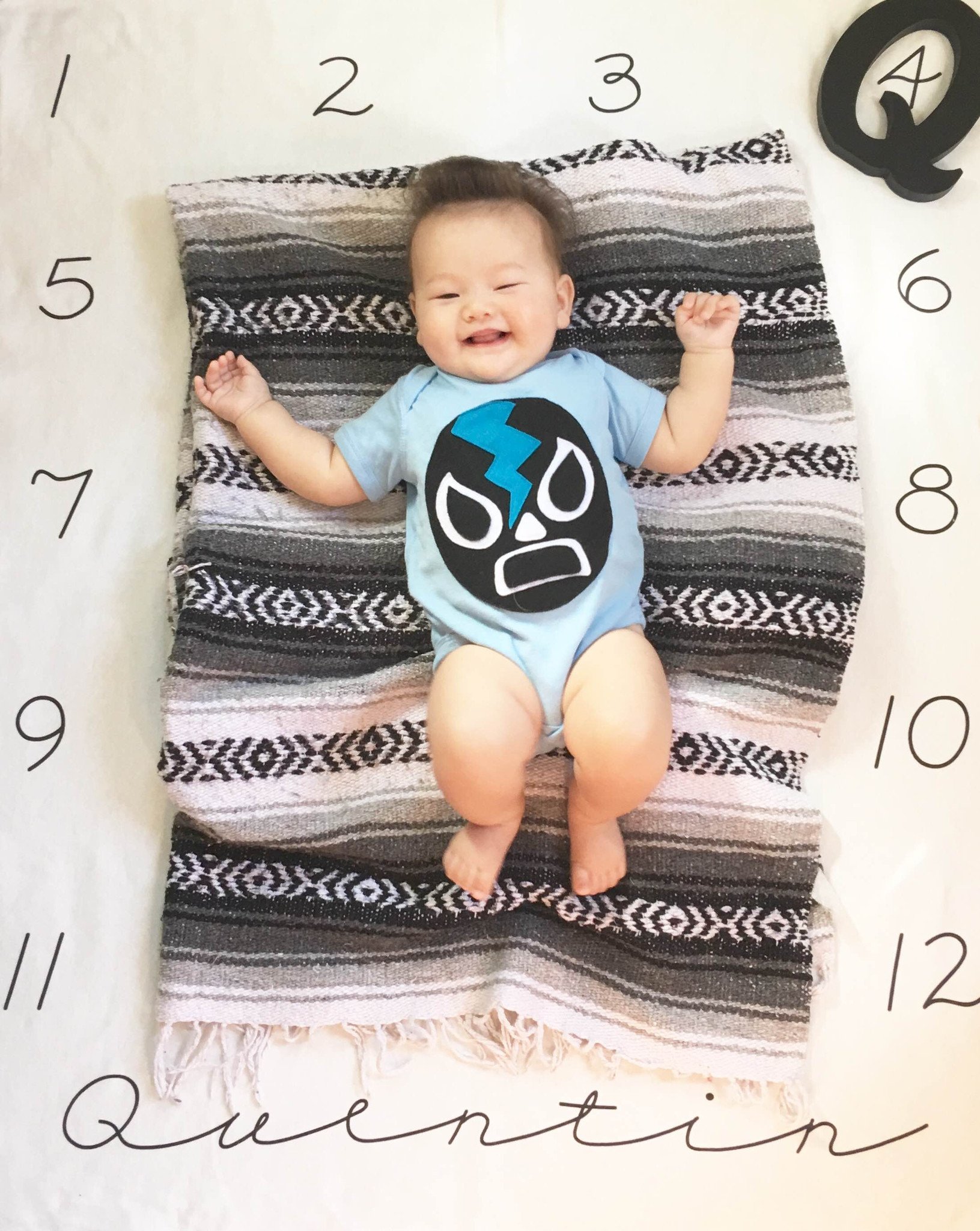 A colorful Baby Onesie featuring the Luchador Negro design, showcasing a vibrant Mexican wrestler character, perfect for infants.