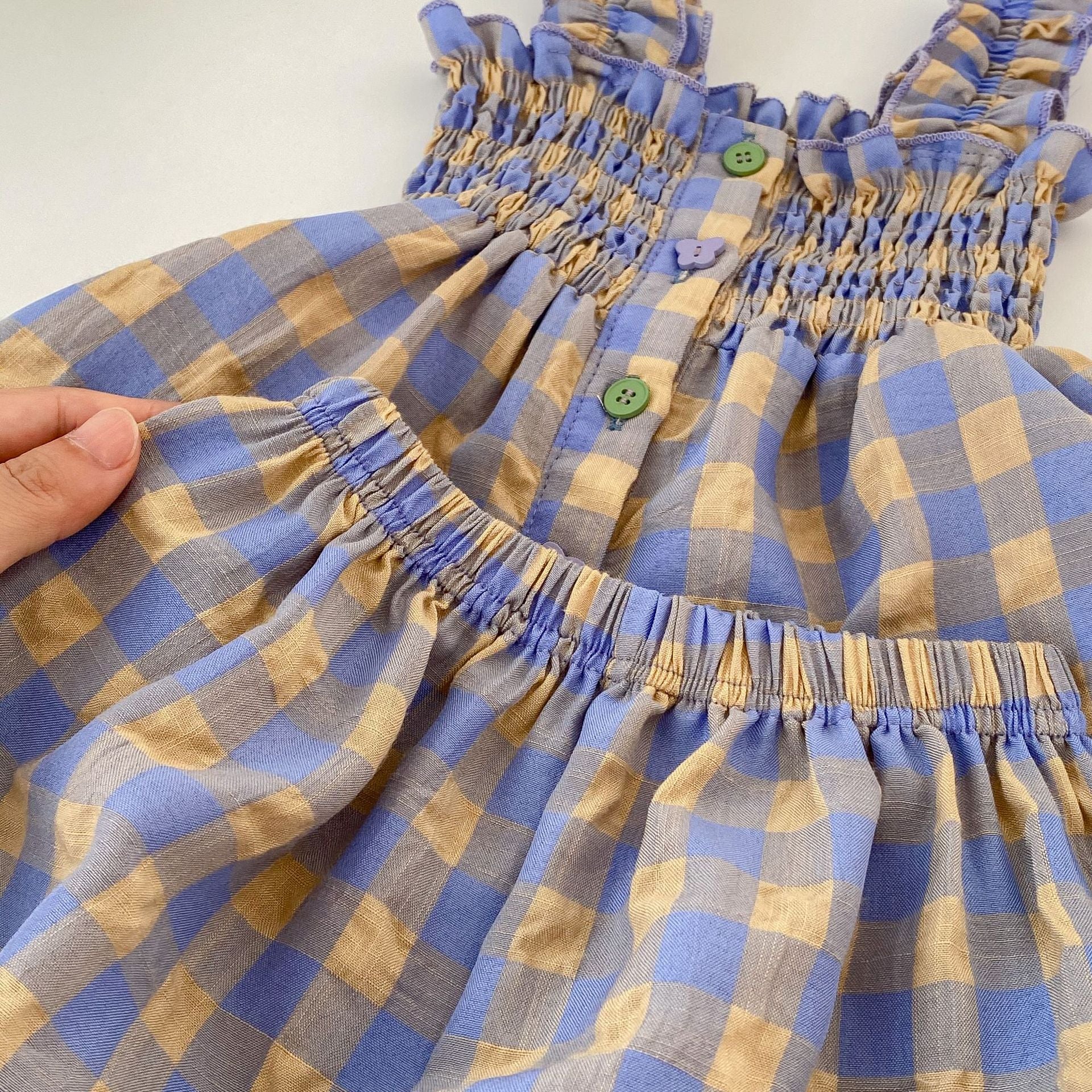 Adorable baby girl wearing a blue plaid pattern sling blouse with matching shorts, perfect for summer outings.