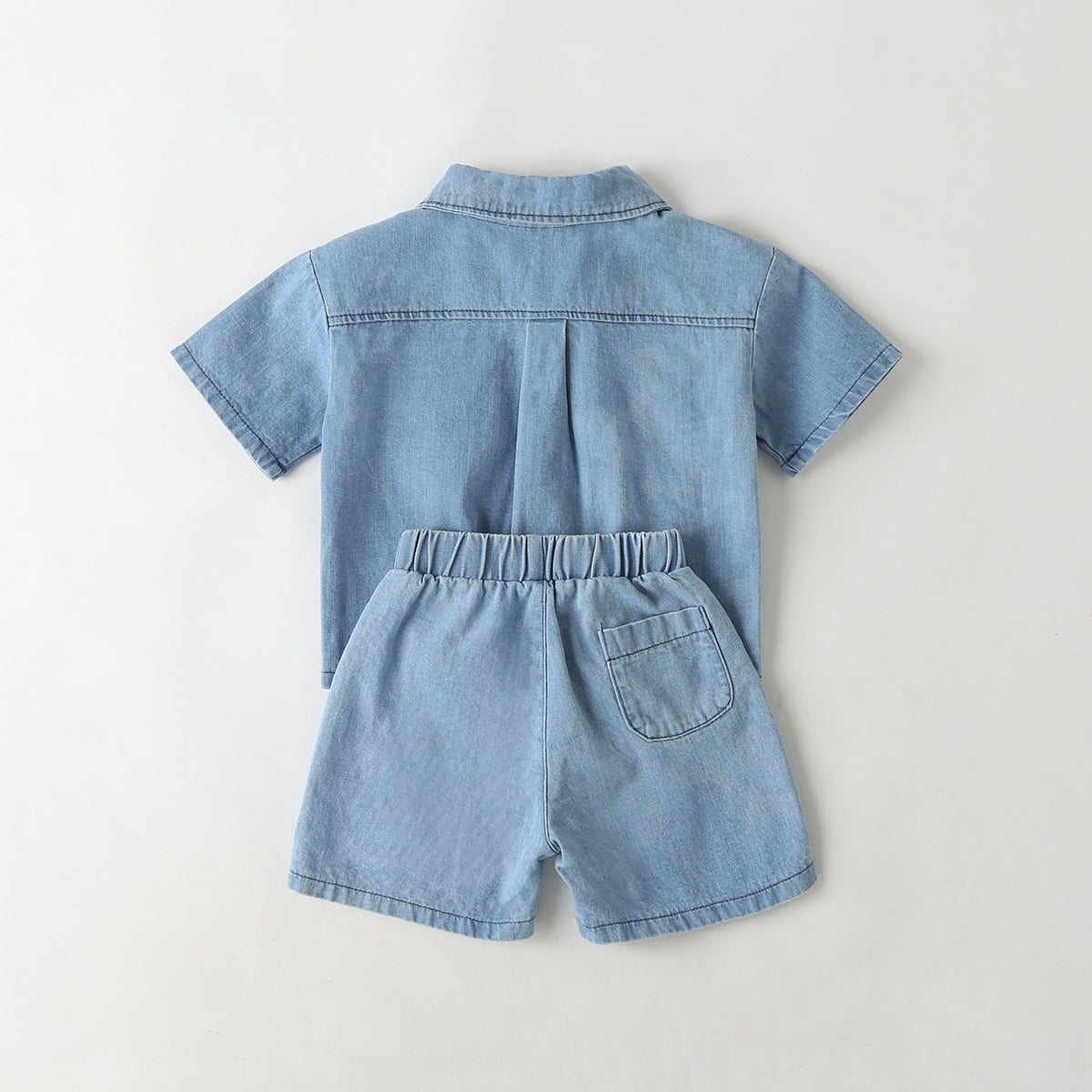 Baby wearing a solid color button front denim shirt and shorts set in blue, perfect for summer outings.
