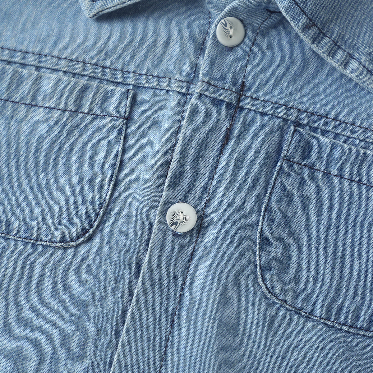 Baby wearing a solid color button front denim shirt and shorts set in blue, perfect for summer outings.