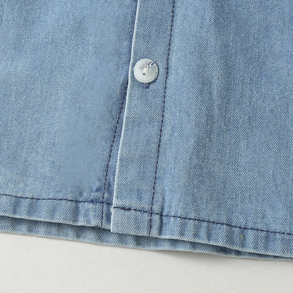 Baby wearing a solid color button front denim shirt and shorts set in blue, perfect for summer outings.